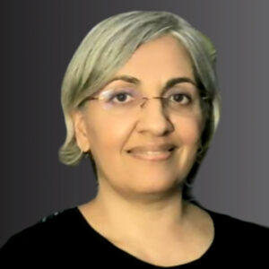 The head of a woman facing the camera. She has short hair, glasses and wears a black top