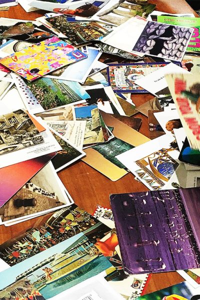 A tabletop covered in old postcards during a Train the trainer session. Several hands reach in, each picking up a card.